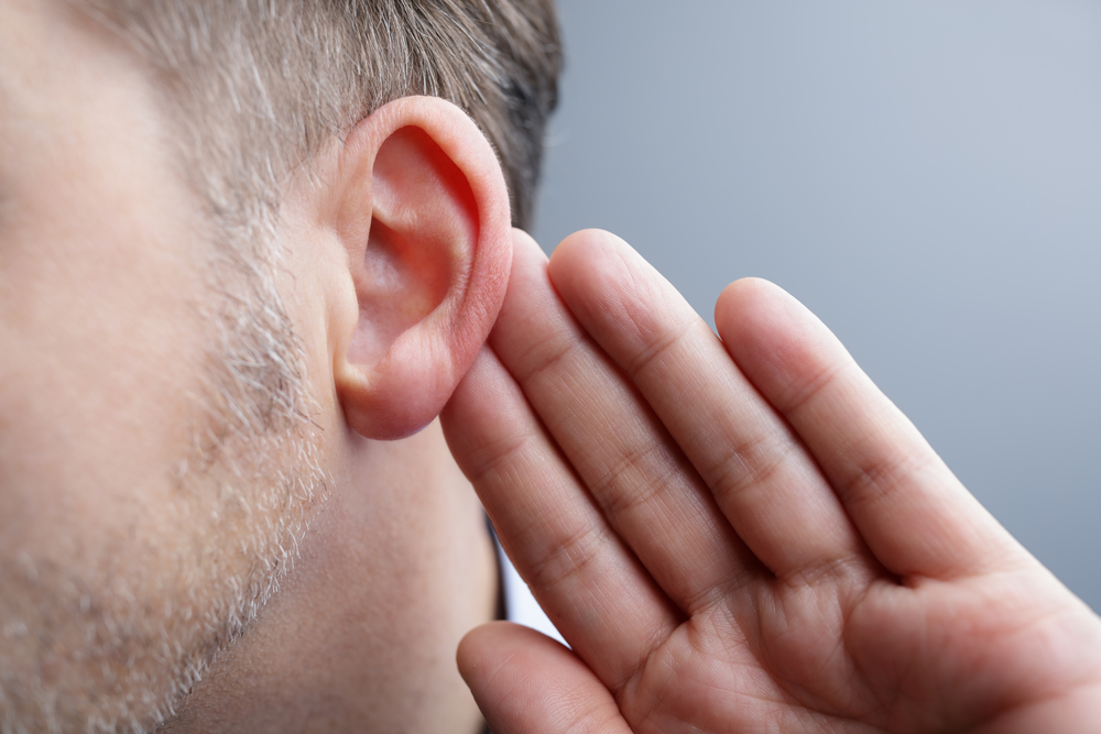 Man with hand on ear listening